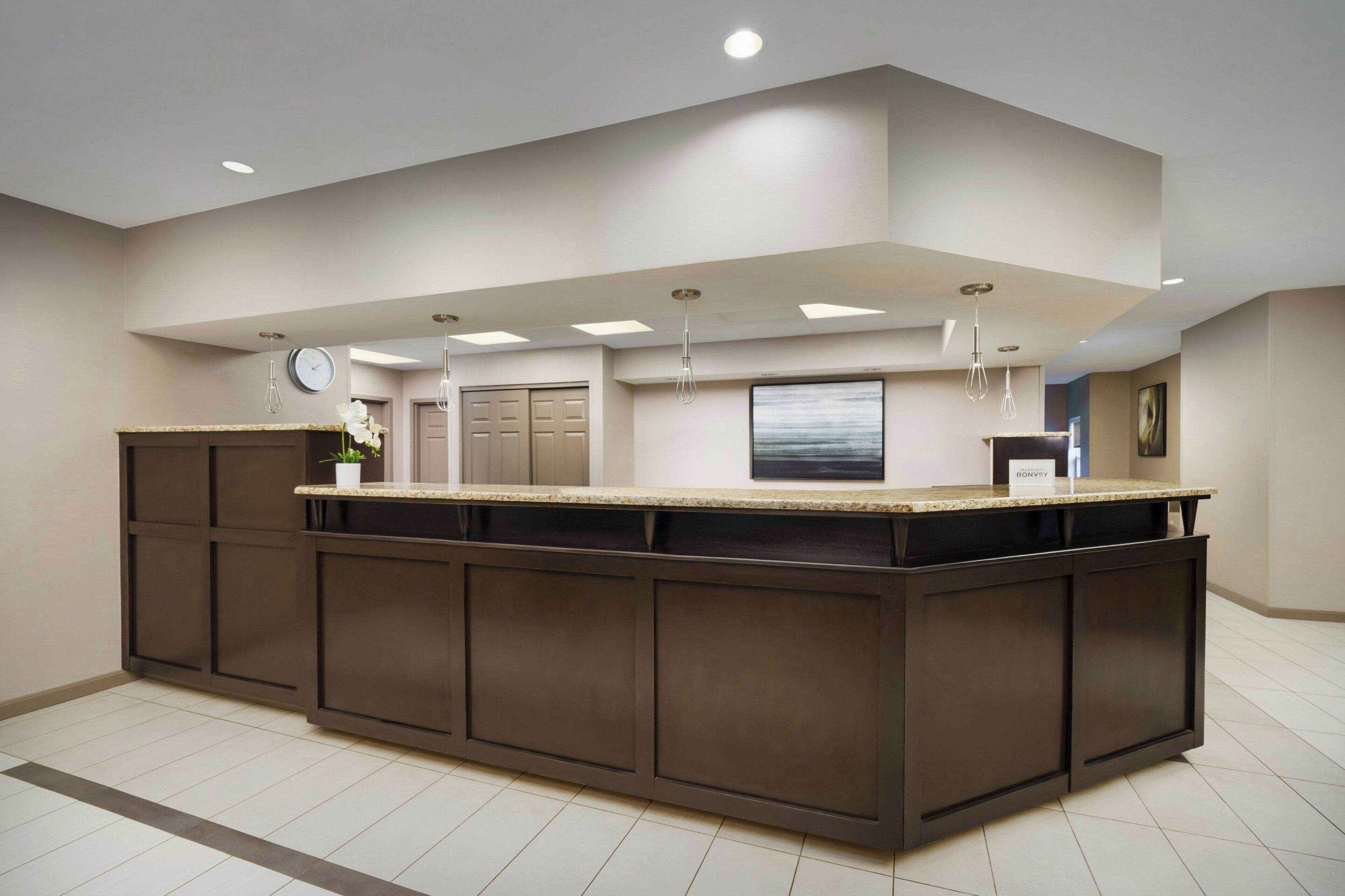 A modern kitchen with a central island, recessed ceiling lights, and a clock on the wall.
