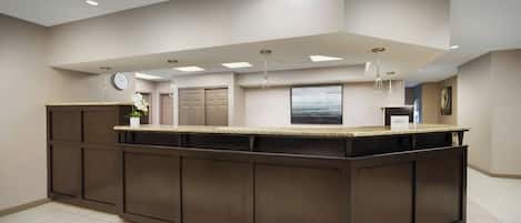 A modern kitchen with a central island, recessed ceiling lights, and a clock on the wall.