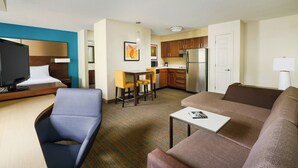 A hotel room with a bed, a TV, a desk, a sofa, a small table, a kitchen area, and a dining table with chairs. - Residence Inn by Marriott Portland Scarborough (Scarborough)