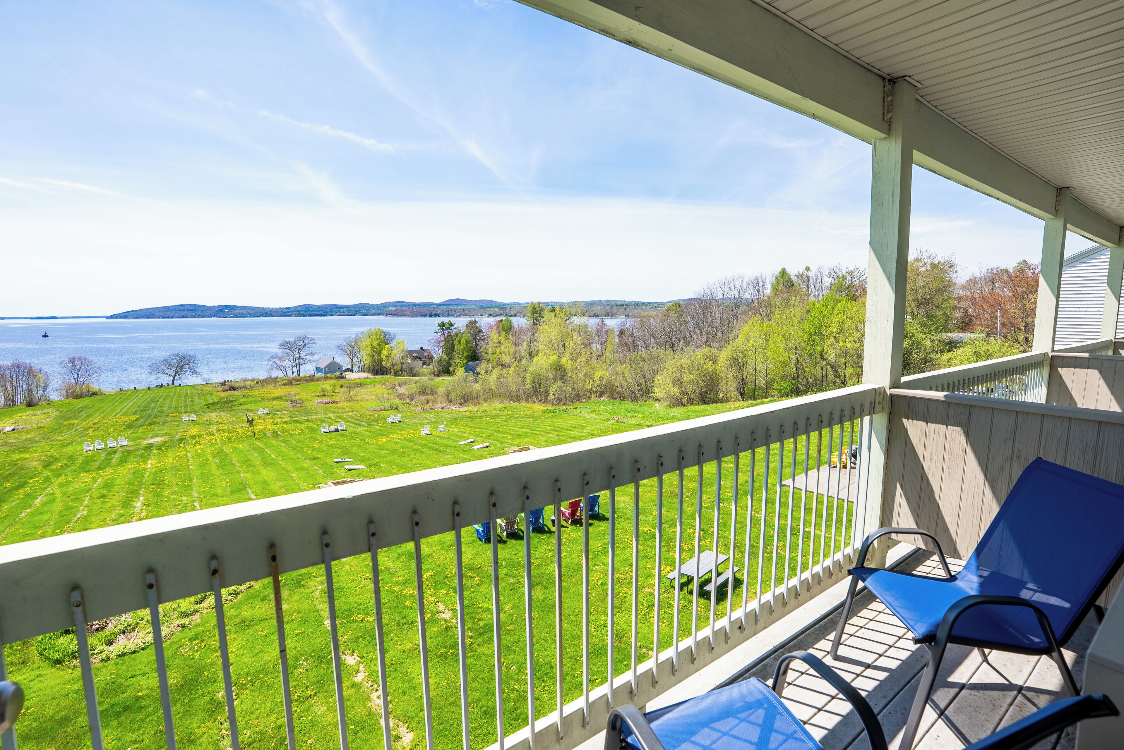 A balcony with a view of a grassy field and a body of water.