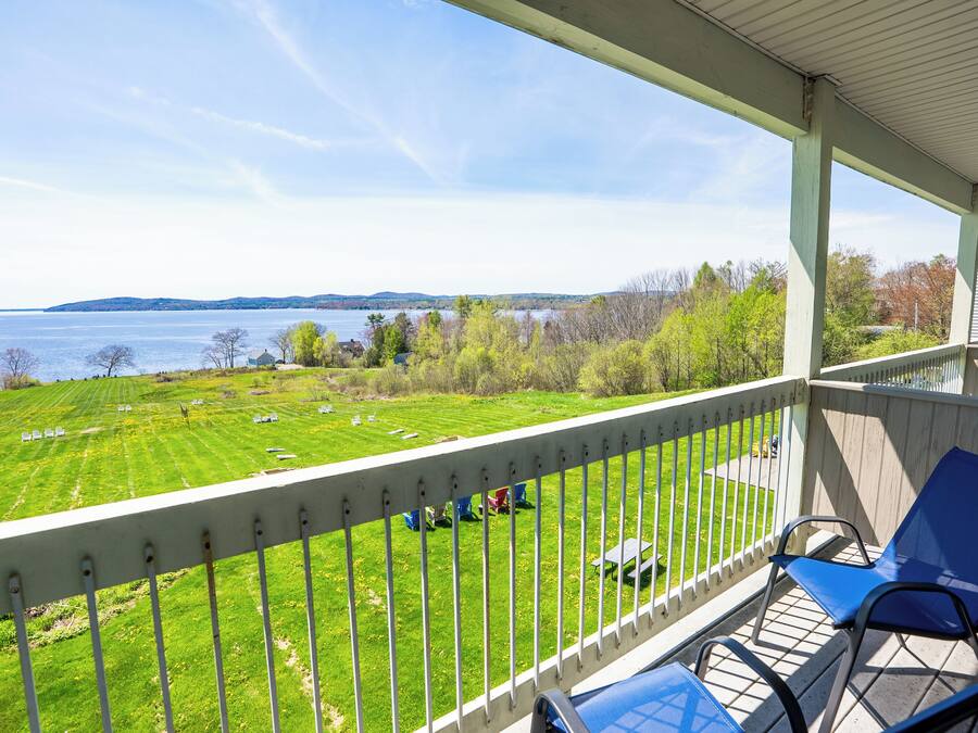 A balcony with a view of a grassy field and a body of water.