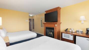 A hotel room with two beds, a fireplace, a television, a microwave, and a coffee maker.