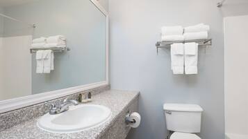 A bathroom with a granite countertop sink, a toilet, and towel racks on the wall.
