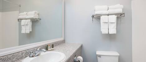Un baño con lavamanos de encimera de granito, inodoro y toalleros en la pared.