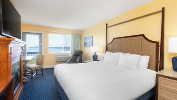 Une chambre d’hôtel avec un grand lit, une télévision, une chaise, un bureau et une fenêtre donnant sur la mer.