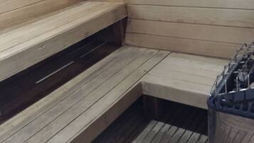 Uma sauna com bancos de madeira e um recipiente metálico, provavelmente para água ou vapor.