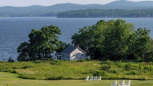 A house by a lake with a grassy lawn and four Adirondack chairs. - Fireside Inn & Suites - Belfast (Belfast)