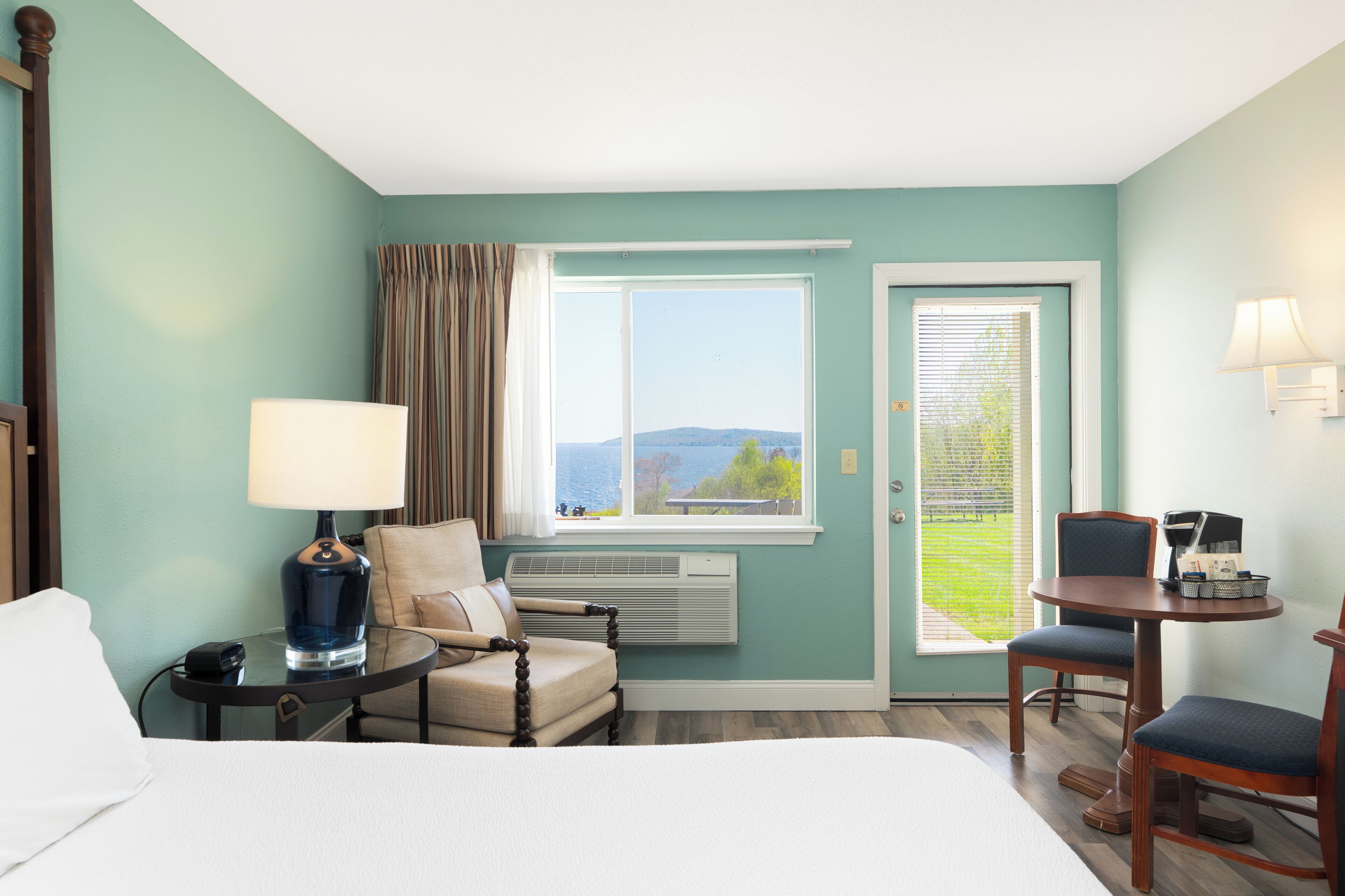 Habitación de hotel con cama, una silla, una mesa, una lámpara, un calefactor y vistas al exterior.