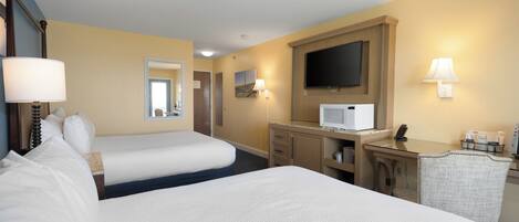 Habitación de hotel con dos camas, un escritorio con computadora, un televisor y un espejo.