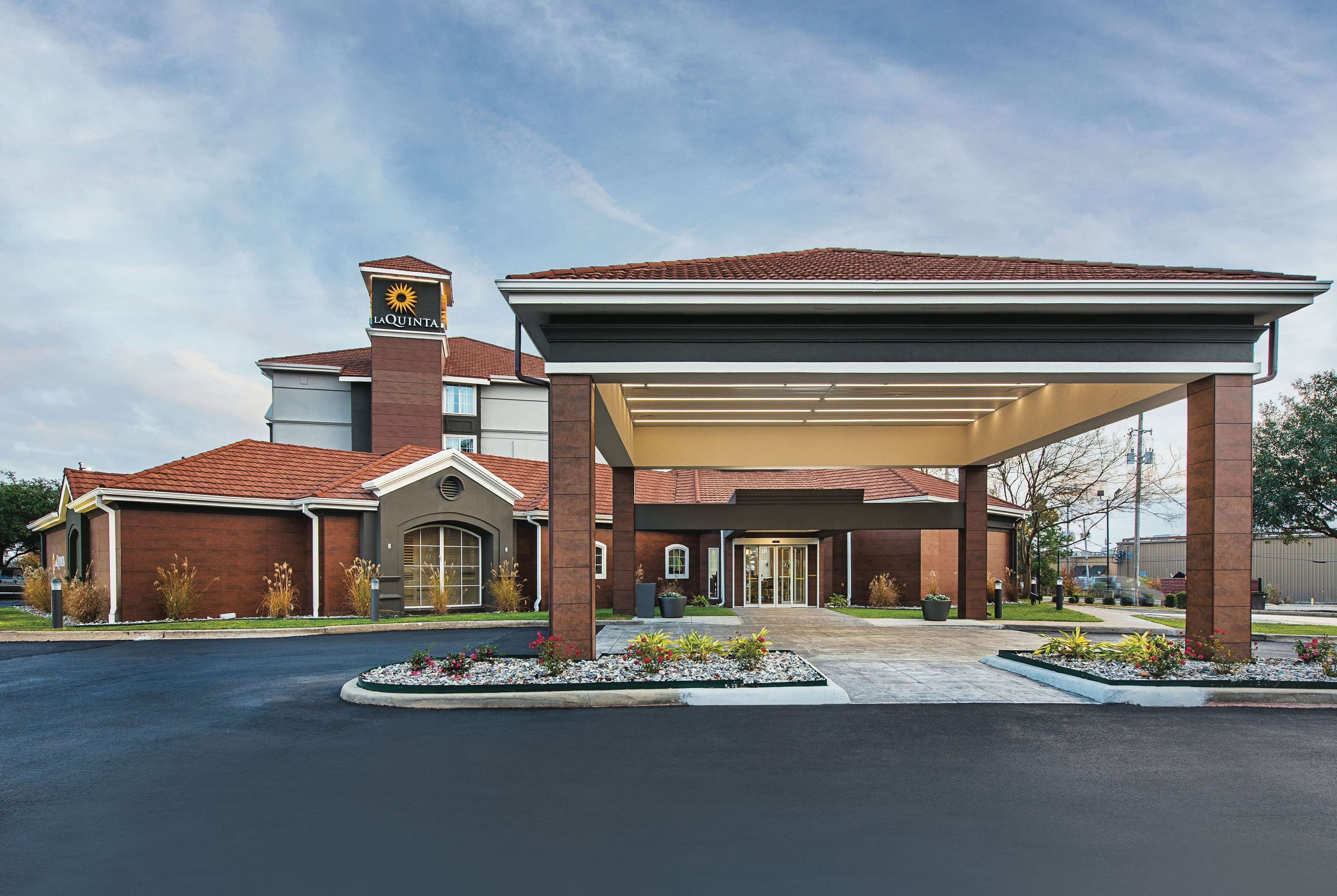A hotel with a covered entrance, a prominent sign, and a landscaped driveway.