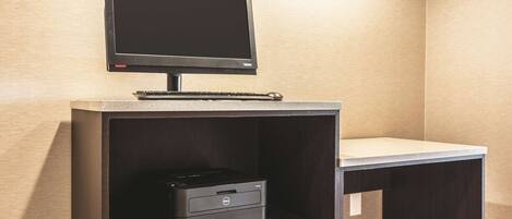 A desk with a monitor, keyboard, and printer.