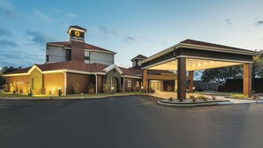 Um hotel com um grande letreiro 'La Quinta', área de estacionamento coberta e entrada bem cuidada.