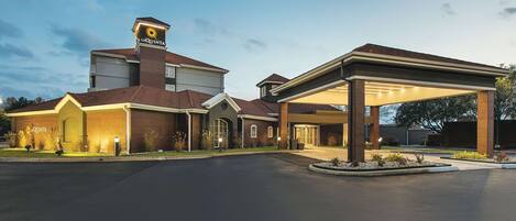 A hotel with a prominent 'La Quinta' sign, a covered parking area, and a well-maintained entrance.