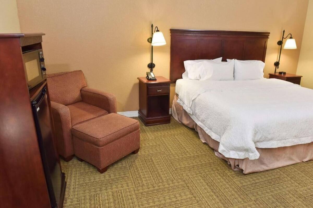 Ett hotellrum med en säng, en stol, ett skrivbord med en dator och två sänglampor.