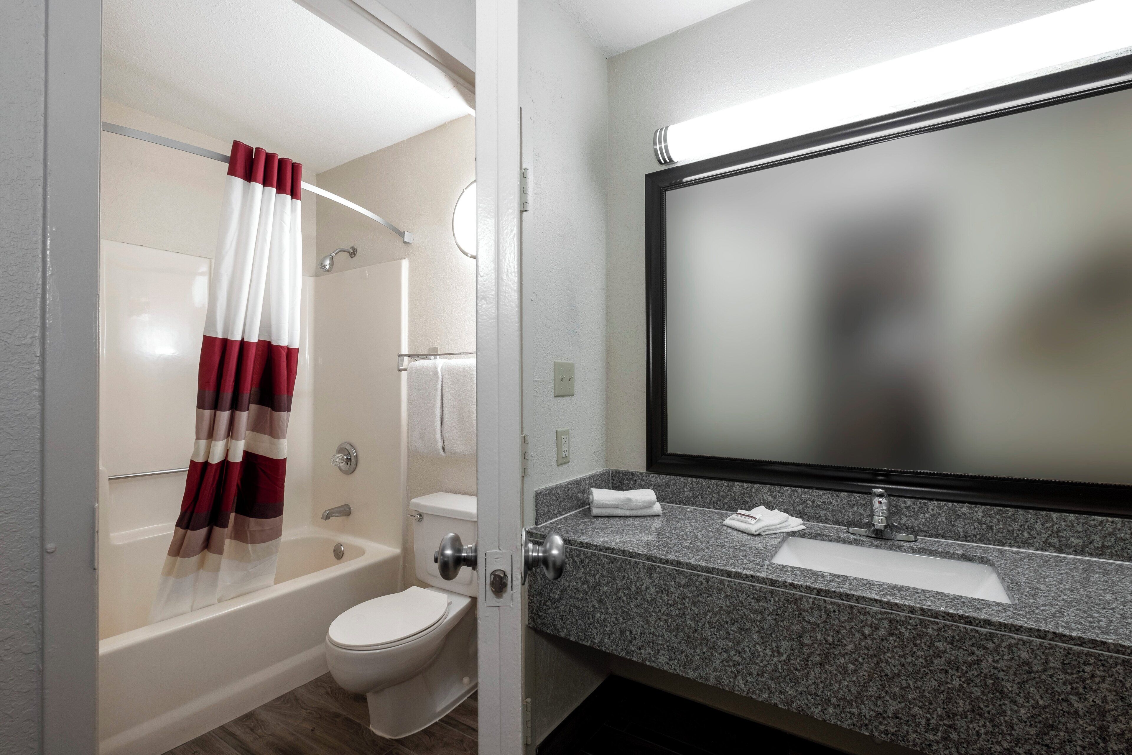 Un baño con bañera, inodoro y tocador con espejo.