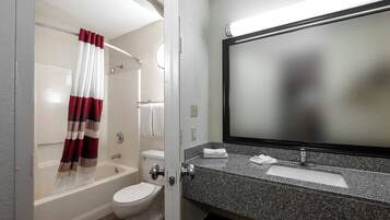 Un baño con bañera, inodoro y tocador con espejo.