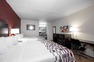 Una habitación de hotel con una cama grande, un escritorio con una silla, un televisor y un espejo.