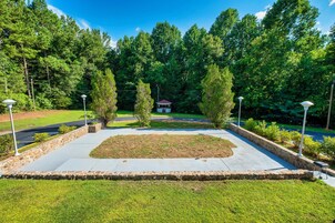 Un jardín ajardinado con césped central, bordes de piedra y un pabellón.