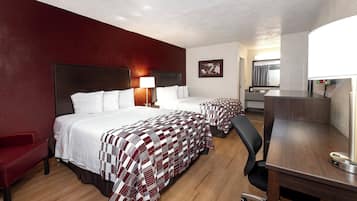 Een hotelkamer met twee bedden, een bureau, een stoel, een lamp en een schilderij aan de muur.