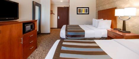 A hotel room with a bed, a TV, a desk with a lamp, and a wardrobe.