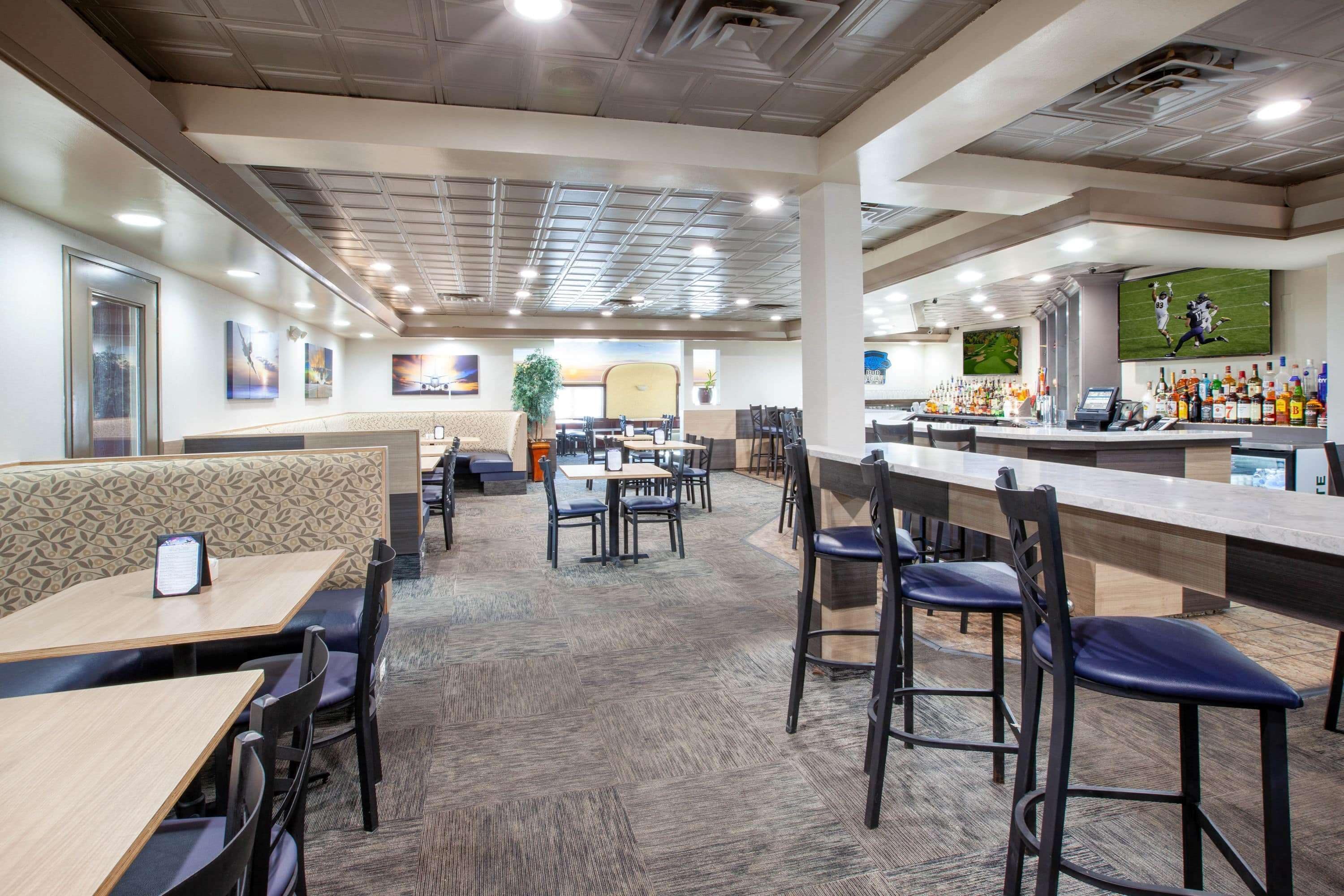 A restaurant with booths and tables, a bar area with a counter and stools, and artwork on the walls.
