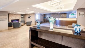 A modern reception area with a wooden reception desk, grey sofas, and a large vase.