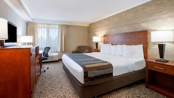 Une chambre d’hôtel avec un grand lit, un bureau avec une chaise, une télévision et une lampe.