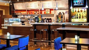 A restaurant with a bar area, tables, chairs, and a menu board. - Courtyard by Marriott Detroit Utica (Utica)