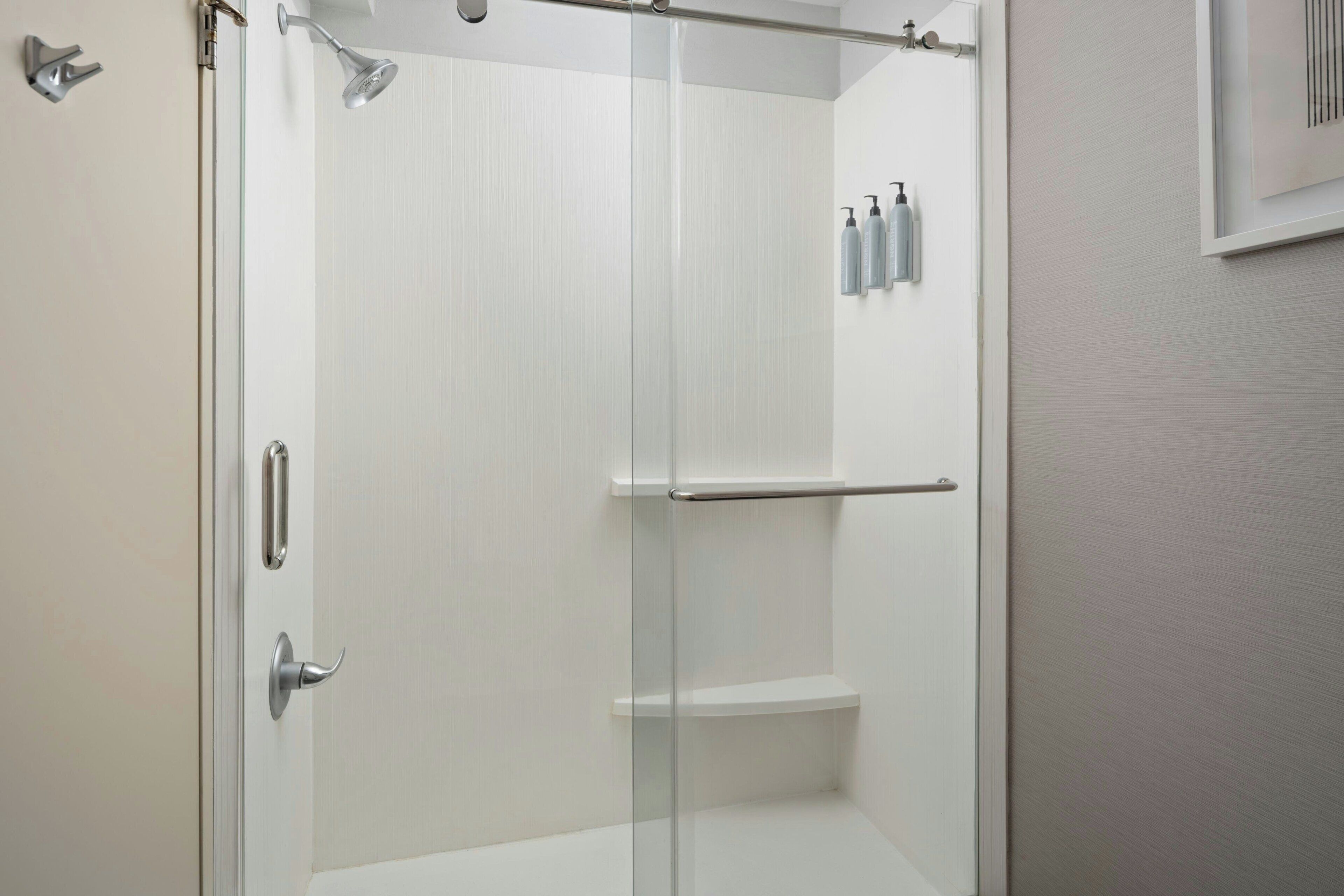 A modern bathroom with a glass shower enclosure, a white sink, and a mirror.