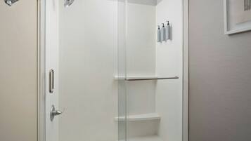 A modern bathroom with a glass shower enclosure, a white sink, and a mirror.