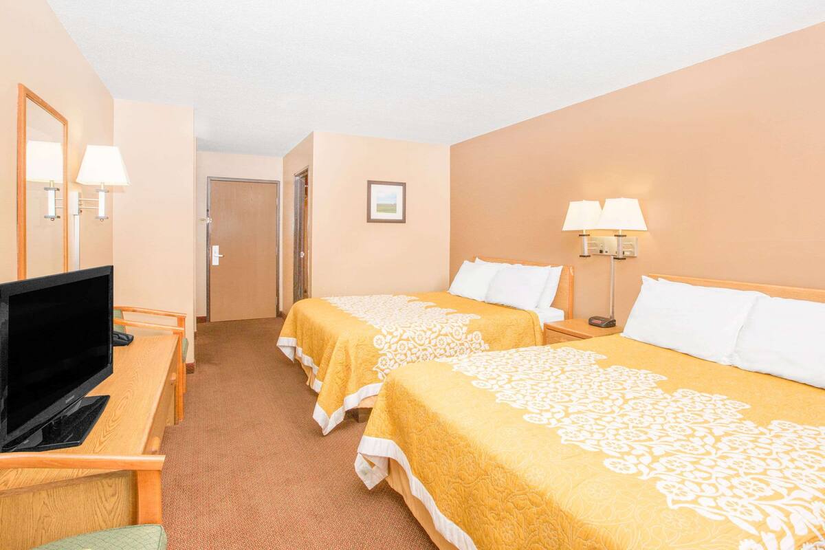 A hotel room with two beds, a desk with a computer, and a TV.