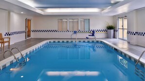 An indoor swimming pool with clear water, a diving board, and a chair. - Fairfield Inn by Marriott Hattiesburg (Hattiesburg)