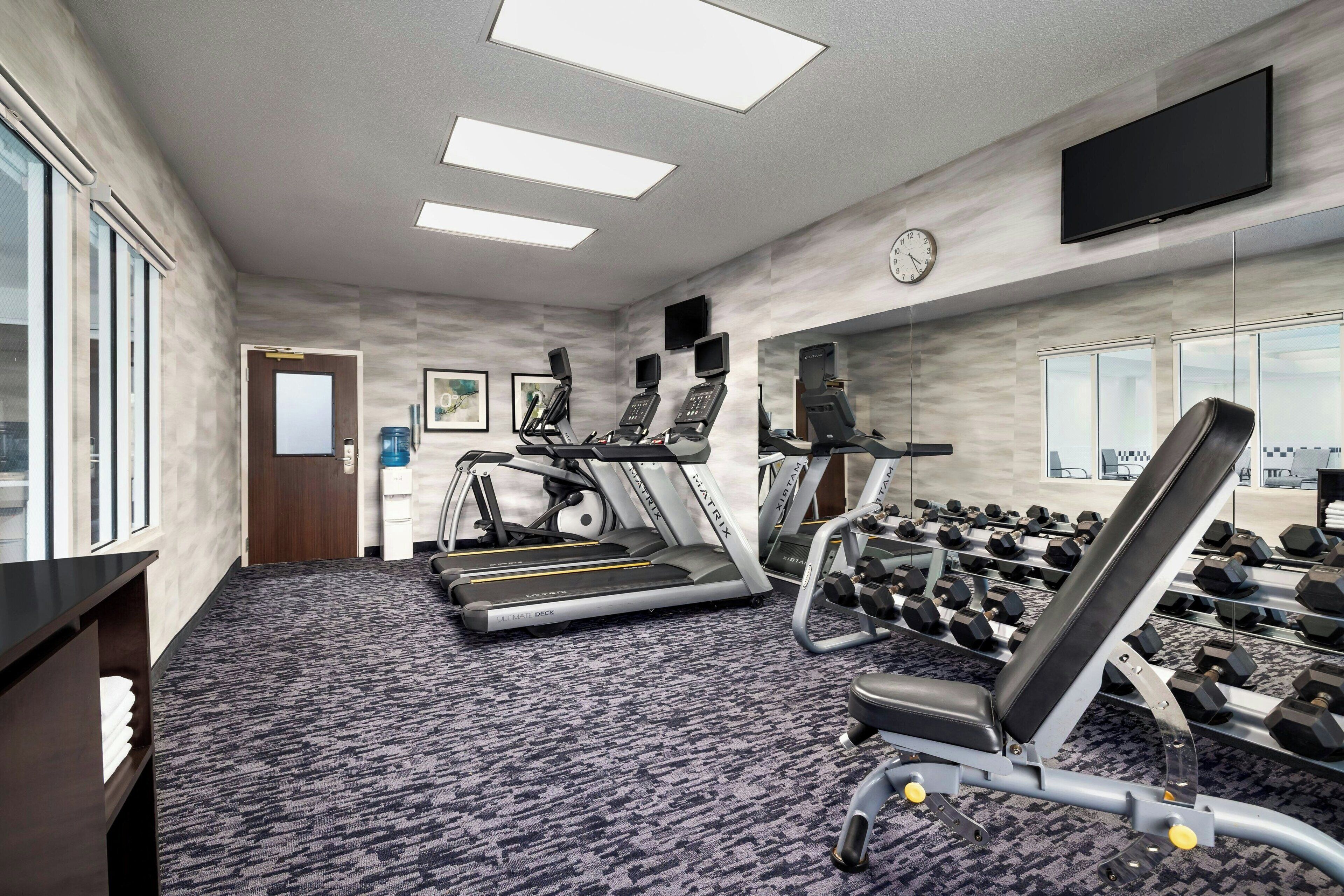 Un gimnasio con cintas de correr, máquinas de pesas y mancuernas.