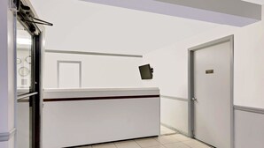 Un comptoir d’accueil avec une pancarte indiquant qu’il est réservé aux employés, une porte sur la droite et une fenêtre sur la gauche.