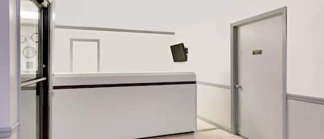 Una recepción con un letrero que indica que es solo para empleados, una puerta a la derecha y una ventana a la izquierda.