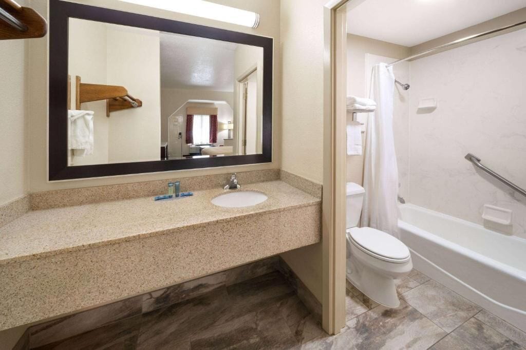 A bathroom with a sink, mirror, toilet, and bathtub.