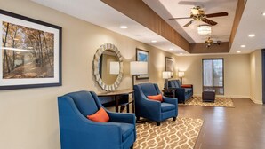 A spacious living area with two blue armchairs, a round mirror, and a large framed picture on the wall. - Comfort Inn Pearl-Jackson (Pearl)