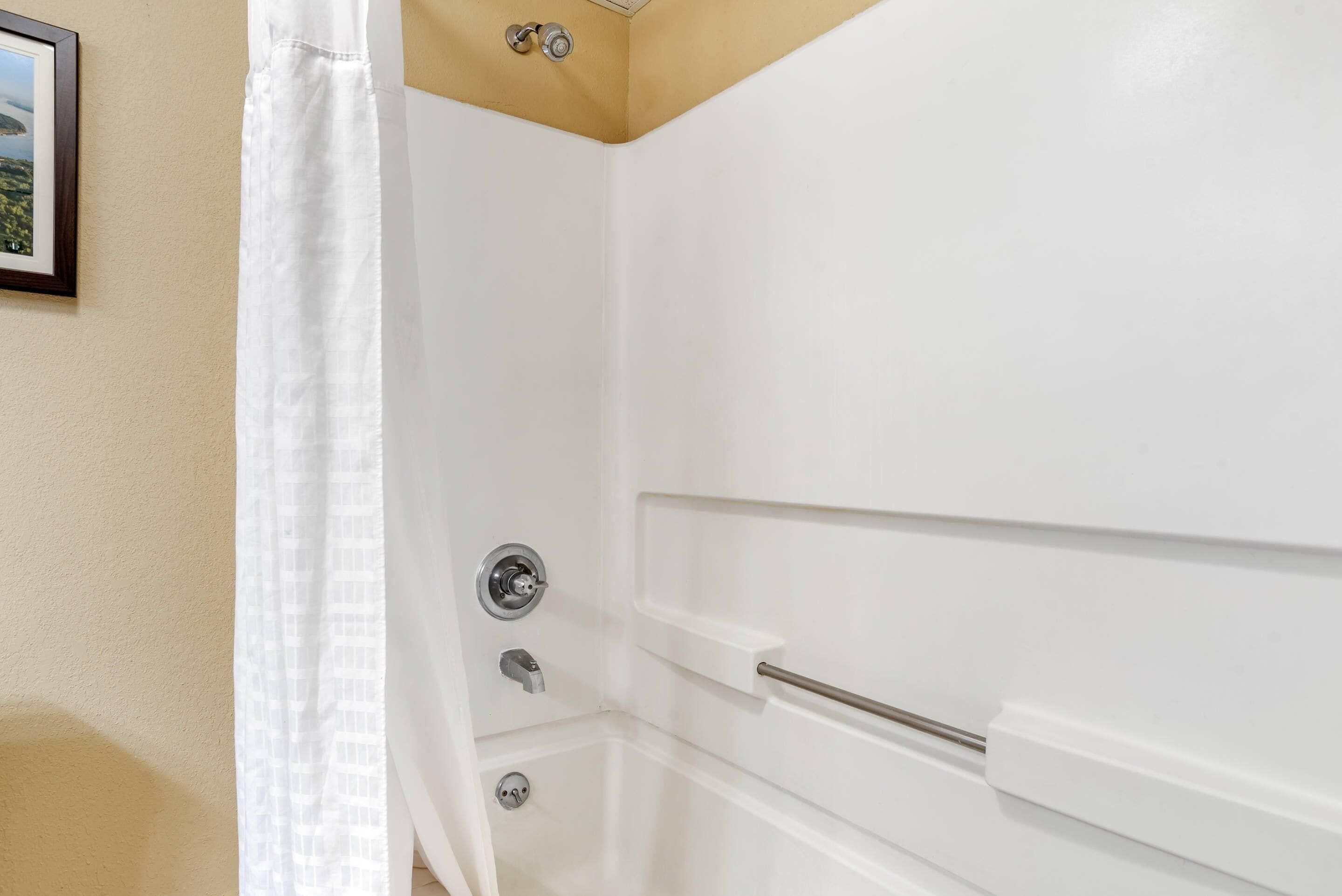 A white bathroom with a shower door, a towel rack, and a framed picture on the wall.