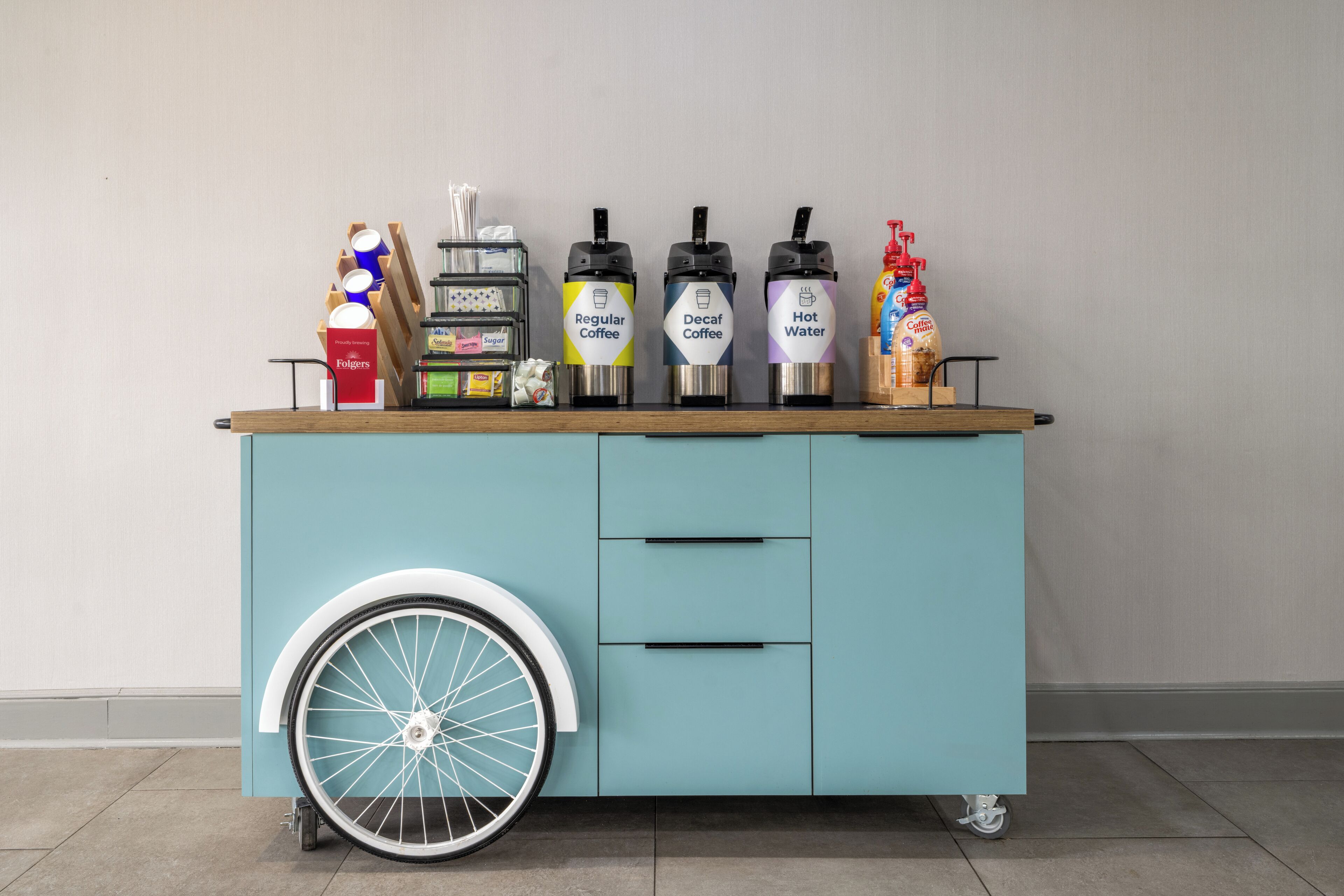 A stationary cart with beverage dispensers and a wheelchair-accessible wheel.