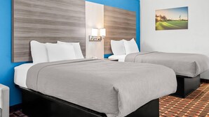 A hotel room with two beds, a nightstand, a lamp, and a painting of a golf course. - Quality Inn Aiken North (Aiken)