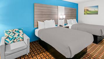 Habitación de hotel con dos camas, un sofá, piso estampado y un cuadro en la pared.