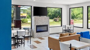 A modern indoor seating area with a fireplace, large windows, and a flat-screen TV. - Quality Inn Aiken North (Aiken)