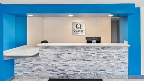 A reception desk with a 'Quality by Choice Hotels' sign, a stone-textured counter, and a blue accent wall. - Quality Inn Aiken North (Aiken)