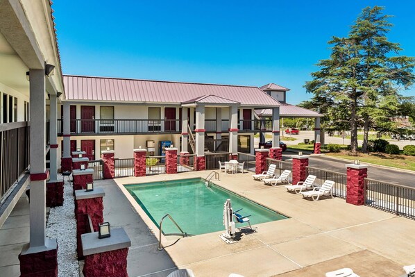 A hotel with a swimming pool, outdoor seating, and a red and white color scheme. - Quality Inn Aiken North (Aiken)