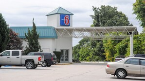 Un motel reconnaissable à son grand panneau indiquant le chiffre « 6 », à son passage couvert et aux véhicules qui y sont garés.