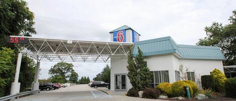 Un motel con área de estacionamiento techada y un letrero que indica un precio de $55.99.