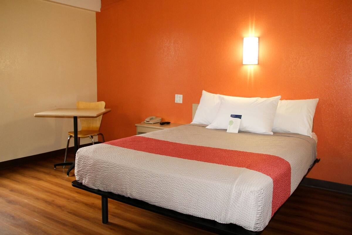 A hotel room with a bed, a desk, and a nightstand.