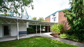 Un espace extérieur abrité comprenant un banc, une pelouse et un bâtiment à la façade en briques.