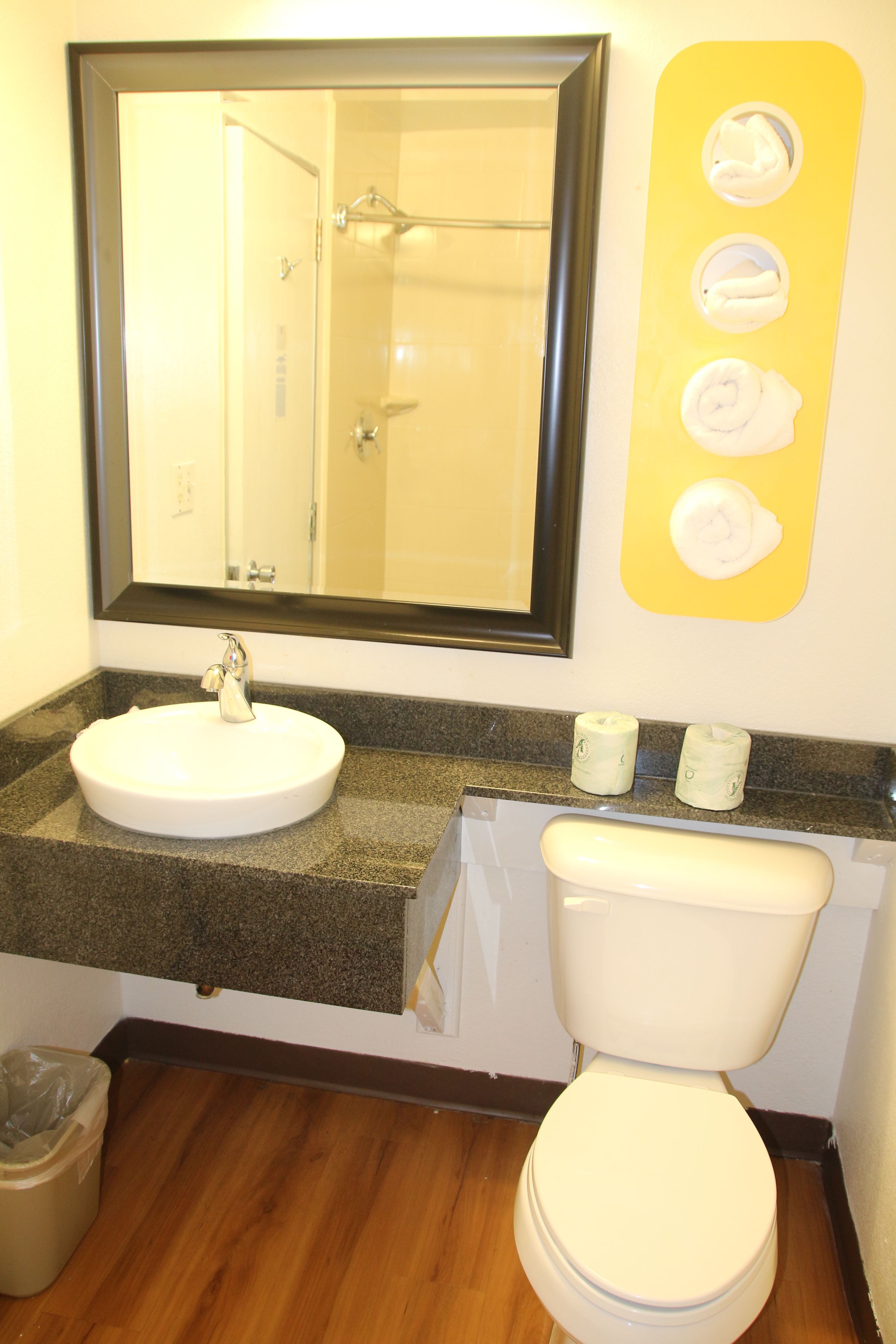 Une salle de bain équipée d’un lavabo, d’un miroir, de toilettes et d’un distributeur de serviettes.