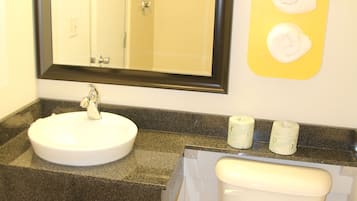 Ein Badezimmer mit Waschbecken, Spiegel, Toilette und Seifenspender.